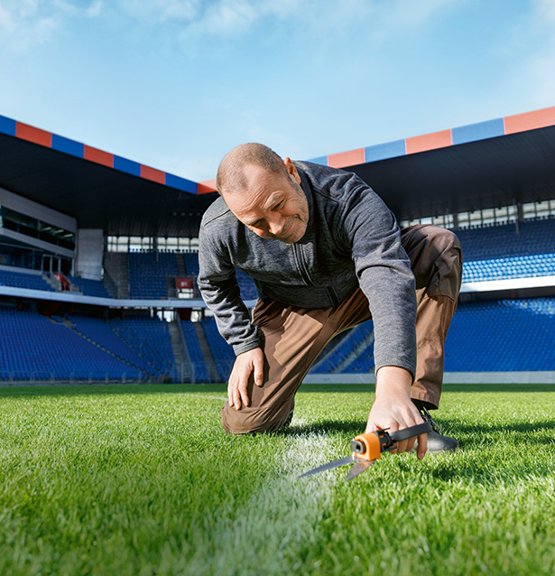 Greenkeeper schneidet Grass auf Fussballfeld.